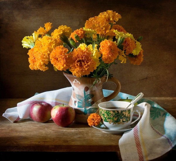 Оранжевые цветы в кувшине, яблоки, чайная чашка